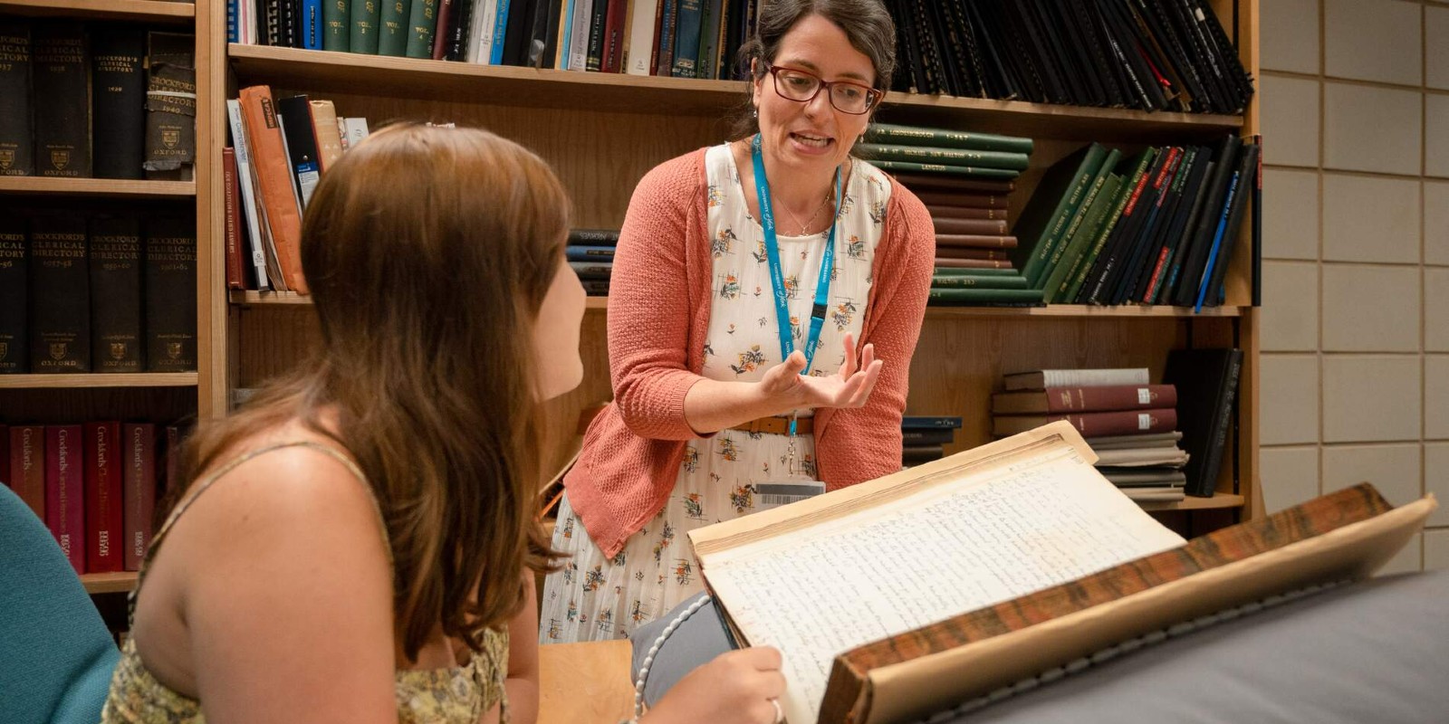 A staff member instructing a student while viewing archive material